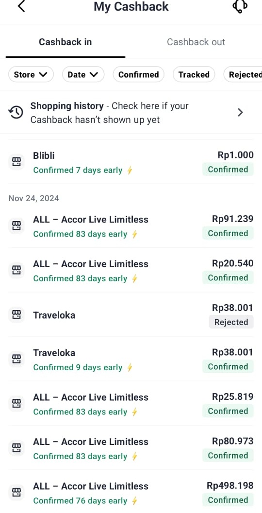 Orang tersenyum memegang smartphone dengan tampilan aplikasi cashback