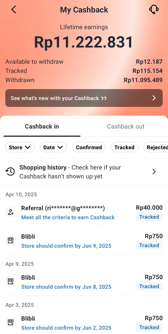 Orang tersenyum memegang smartphone dengan tampilan aplikasi cashback