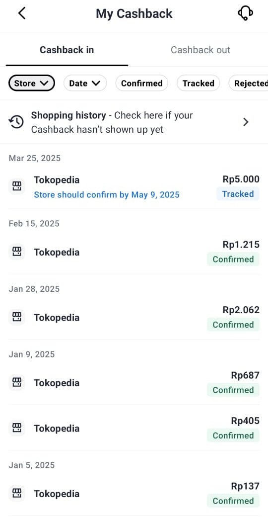 Orang tersenyum memegang smartphone dengan tampilan aplikasi cashback