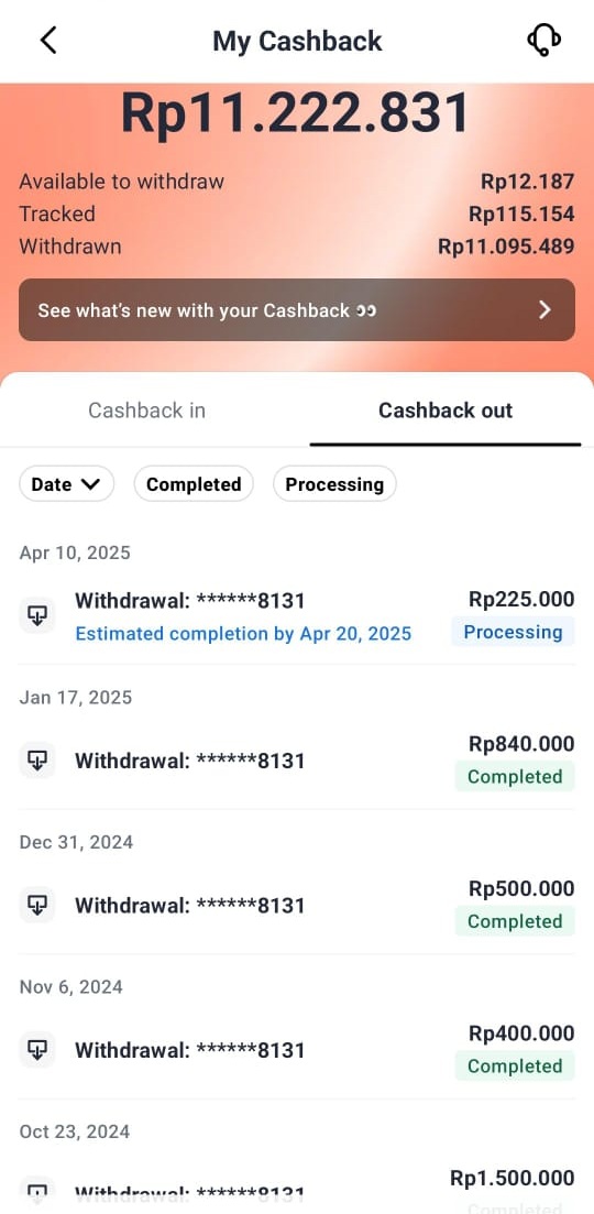 Orang tersenyum memegang smartphone dengan tampilan aplikasi cashback